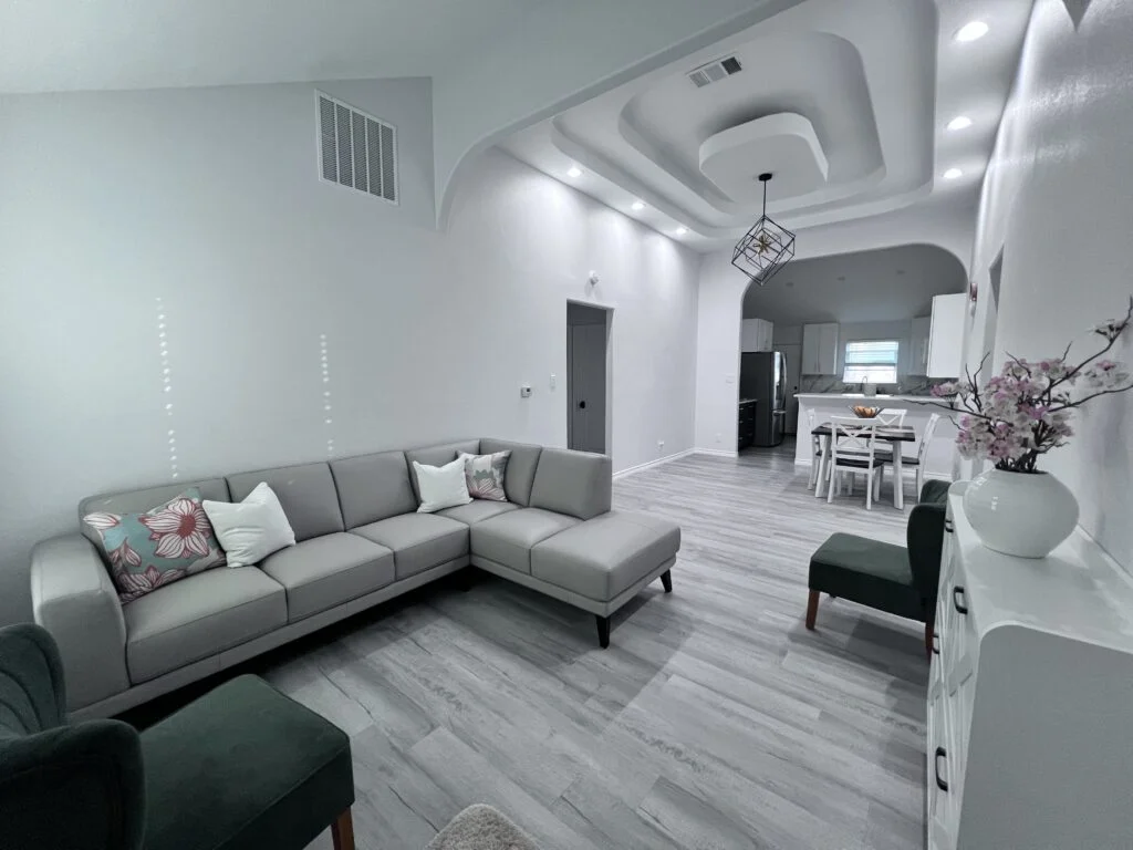 Open concept living room interior with grey sectional sofa and modern ceiling design by JD Local Builders San Antonio TX